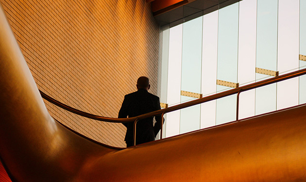 A man stands in a business corridor facing a window