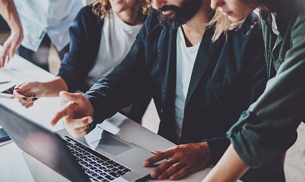 Group of professionals working around a computer, collaborating on work